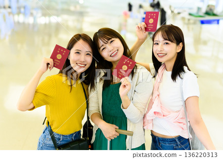Three women holding up their passports ■Photography cooperation: Kansai International Airport (KIX) 136220313