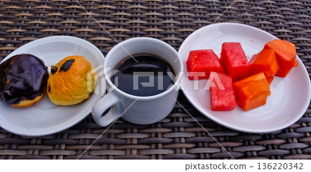 close up photo of a cup of bitter black coffee and a bread snack 136220342