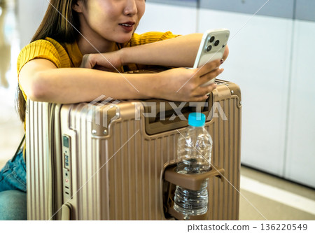 A woman using a smartphone at the airport. Photo courtesy of Kansai International Airport (KIX) 136220549