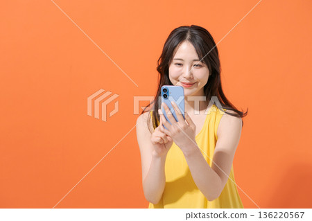 Smiling woman holding a smartphone 136220567