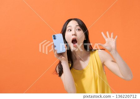 一位表情驚訝的女子拿著智慧型手機 一位表情驚訝的女子拿著智慧型手機 136220712