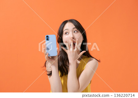 一位表情驚訝的女子拿著智慧型手機 一位表情驚訝的女子拿著智慧型手機 136220714