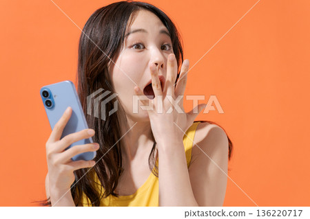 一位表情驚訝的女子拿著智慧型手機 136220717