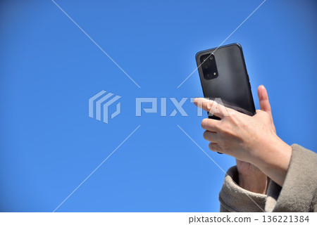 Senior woman talking on a mobile phone under the blue sky Senior woman talking on a mobile phone under the blue sky 136221384
