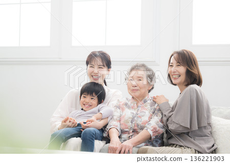 一張幸福的紀念照，照片中四代同堂的祖母、母親和孩子（曾孫）在美麗的逆光房間裡微笑擁抱。 136221903