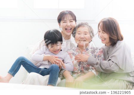 一張四代同堂的全家福,祖母、母親和孩子(曾孫)在美麗的逆光房間裡微笑擁抱,這是一張充滿幸福回憶的父母與子女合影。 一張四代同堂的全家福,祖母、母親和孩子(曾孫)在美麗的逆光房間裡微笑擁抱,這是一張充滿幸福回憶的父母與子女合影。 136221905