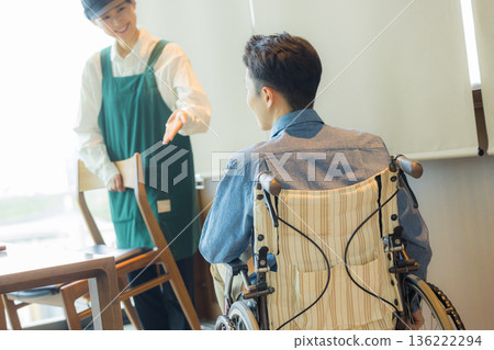 咖啡館裡的一名工作人員正在引導一位坐輪椅的顧客。 136222294