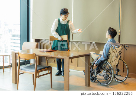 咖啡館裡的一名工作人員正在引導一位坐輪椅的顧客。 136222295