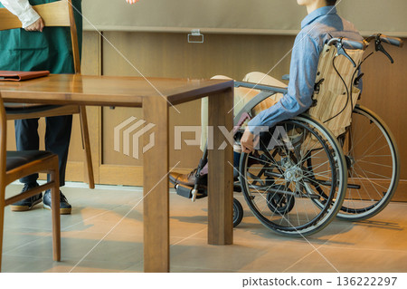 咖啡館裡的一名工作人員正在引導一位坐輪椅的顧客。 咖啡館裡的一名工作人員正在引導一位坐輪椅的顧客。 136222297