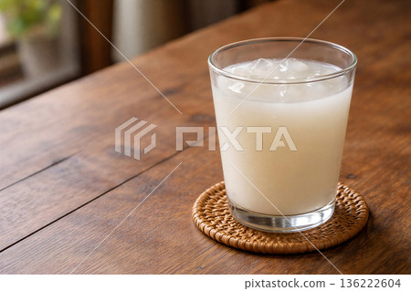 木桌上放著一杯加冰的白色乳酸飲料。 136222604