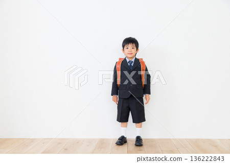 A boy in a suit carrying a school bag 136222843