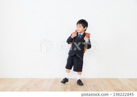 A boy in a suit carrying a school bag A boy in a suit carrying a school bag 136222845