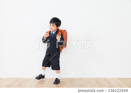 A boy in a suit carrying a school bag 136222849