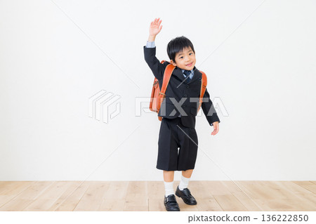 A boy in a suit carrying a school bag 136222850