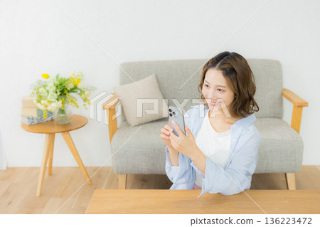 A smiling woman looking at a smartphone A smiling woman looking at a smartphone 136223472