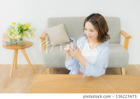 一個微笑的女人看著智能手機 136223473