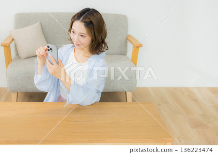 一個微笑的女人看著智能手機 136223474