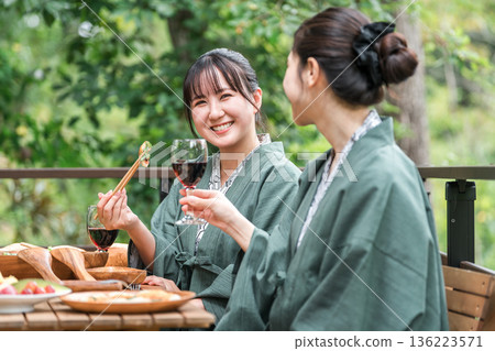 Young Asian woman on a girls trip to a Japanese inn/hot spring inn eating on a balcony/wooden deck (travel/travel) 136223571