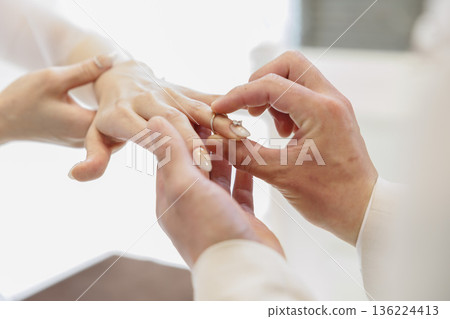 Hands of a man and woman exchanging rings 136224413