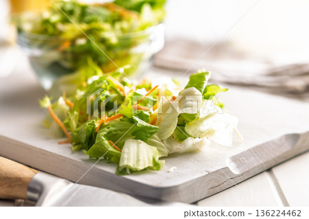 Mix of fresh green salad with carrot on white table. 136224462