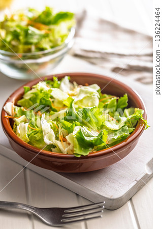 Mix of fresh green salad with carrot in bowl on white table. Mix of fresh green salad with carrot in bowl on white table. 136224464