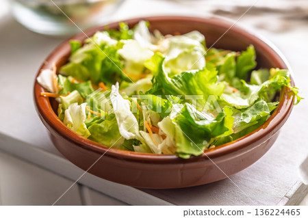 Mix of fresh green salad with carrot in bowl on white table. Mix of fresh green salad with carrot in bowl on white table. 136224465