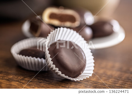Dark chocolate truffles in the shape of coffee beans on wooden table. Dark chocolate truffles in the shape of coffee beans on wooden table. 136224471