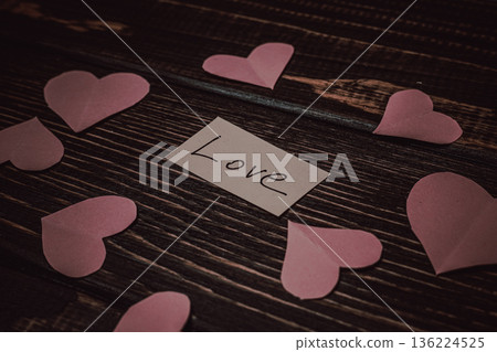 Heart cutouts and a card with love placed on a wooden table Heart cutouts and a card with love placed on a wooden table 136224525