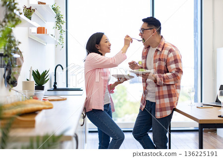 A loving couple enjoys a healthy meal together in their bright, modern kitchen A loving couple enjoys a healthy meal together in their bright, modern kitchen 136225191
