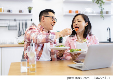 An Asian couple enjoys a healthy meal together at home, with one person feeding the other An Asian couple enjoys a healthy meal together at home, with one person feeding the other 136225197
