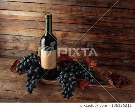 Red wine bottle with blue grapes on an old wooden table. Red wine bottle with blue grapes on an old wooden table. 136225211