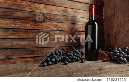 Red wine bottle with blue grapes on an old wooden table. 136225213