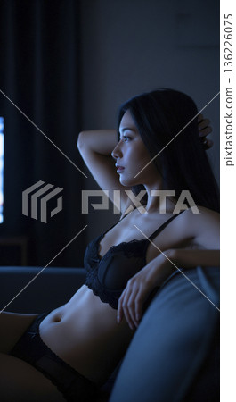 一位身穿黑色內衣的女子正放鬆地躺在沙發上看電視。 136226075