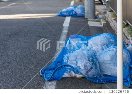 街上堆放著藍鳥網和垃圾袋。 街上堆放著藍鳥網和垃圾袋。 136226756