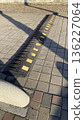 Black rubber speed bump with yellow reflective markings embedded in a pedestrian sidewalk to slow traffic in urban areas.  136227064