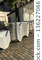 Neatly stacked white plastic chairs arranged in front of a closed beachside booth under bright daylight.  136227066