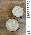 Top view of two beautifully crafted lattes with heart latte art on a wooden table, perfect for cafe or coffee themes.  136227067