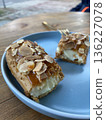 Close-up of a sliced almond pastry on a blue plate with two forks, suggesting a shared sweet treat moment.  136227078