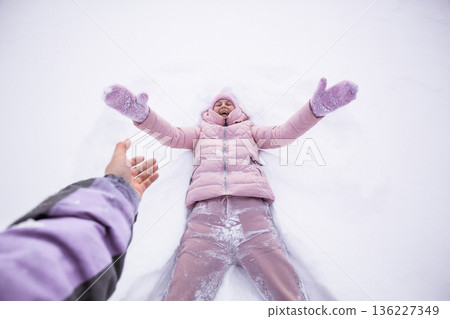 happy woman lying on snow and moving her arms and legs Smiling woman lying on snow in winter holiday happy woman lying on snow and moving her arms and legs Smiling woman lying on snow in winter holiday 136227349