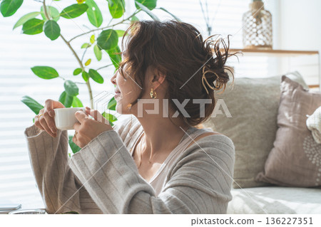 Stylish Asian woman drinking morning coffee in the living room 136227351