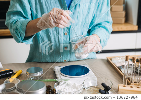 Hands pour powder from plastic packet into glass test tube on digital scale. customized skincare formula, beauty mixology, bespoke wellness gifts, personalized apothecary set. 136227964