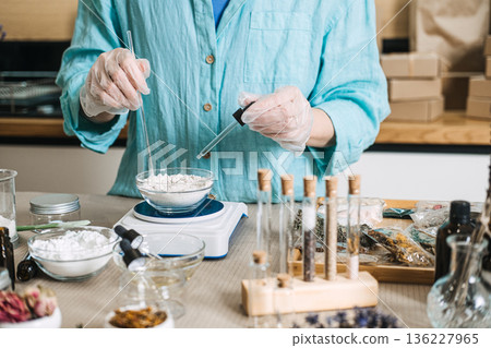 Hands in gloves use dropper and glass rod to mix powder in bowl on electronic scale. Pharmaceutical-grade DIY, wellness technology, bio-hacking beauty, at-home lab equipment. 136227965