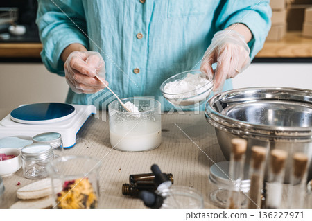 Person wearing gloves adds white powder to liquid mixture among professional laboratory equipment. clean beauty lab, sustainable apothecary, eco-professionalism, sterile skincare making. Person wearing gloves adds white powder to liquid mixture among professional laboratory equipment. clean beauty lab, sustainable apothecary, eco-professionalism, sterile skincare making. 136227971