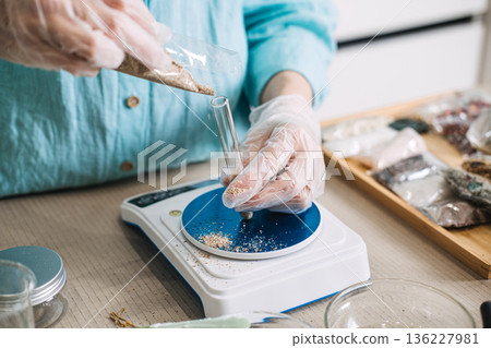Person in gloves pours herbal mixture into glass test tube positioned on digital scale. modern botanical alchemy, lab-to-bath ritual, scientific nature aesthetic, precision herb crafting. Person in gloves pours herbal mixture into glass test tube positioned on digital scale. modern botanical alchemy, lab-to-bath ritual, scientific nature aesthetic, precision herb crafting. 136227981