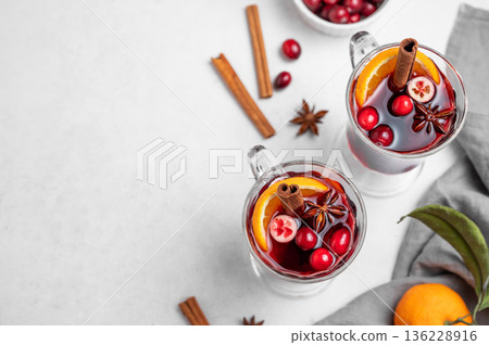Two glasses of mulled wine, orange, cranberry, cinnamon, and star anise on a light background 136228916