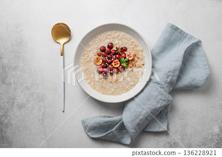 Oatmeal with cranberry, cinnamon and spicy  in a plate on a gray concrete background 136228921