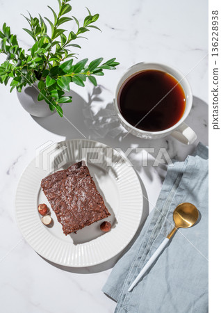 Chocolate brownie on a plate and a cup of espresso coffee on a marble background Chocolate brownie on a plate and a cup of espresso coffee on a marble background 136228938