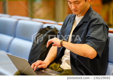 The man checks his watch. Photo courtesy of Kansai International Airport (KIX) The man checks his watch. Photo courtesy of Kansai International Airport (KIX) 136229092