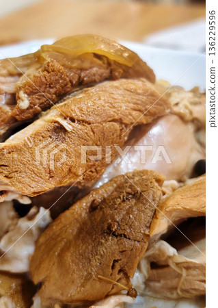 A bowl holds slices of cooked chicken placed with other food items on a wooden table. The meal is ready for serving and eating A bowl holds slices of cooked chicken placed with other food items on a wooden table. The meal is ready for serving and eating 136229596