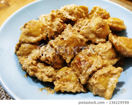 A plate holds pasta covered in a rich sauce made with spices and cream. The dish looks ready for consumption at dinner time A plate holds pasta covered in a rich sauce made with spices and cream. The dish looks ready for consumption at dinner time 136229599